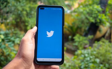 hand holding a smartphone with twitter icon on screen iphone with a social media app logo
